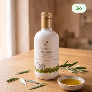 Bouteille d'huile d'olive vierge extra biologique Homenaje 500 ml posée sur une table en bois avec des feuilles d'olivier et un ramequin d'huile d'olive.